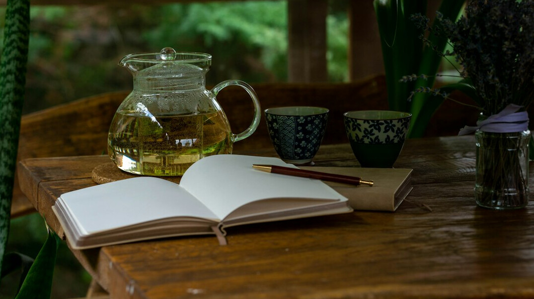 Open notebook with handwritten notes next to a cup of tea